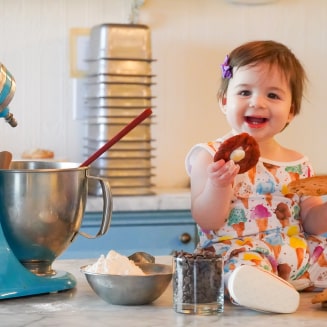 A baby in the kitchen eating cookies