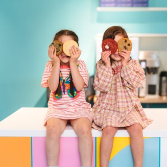 Two children hiding their eyes with cookies